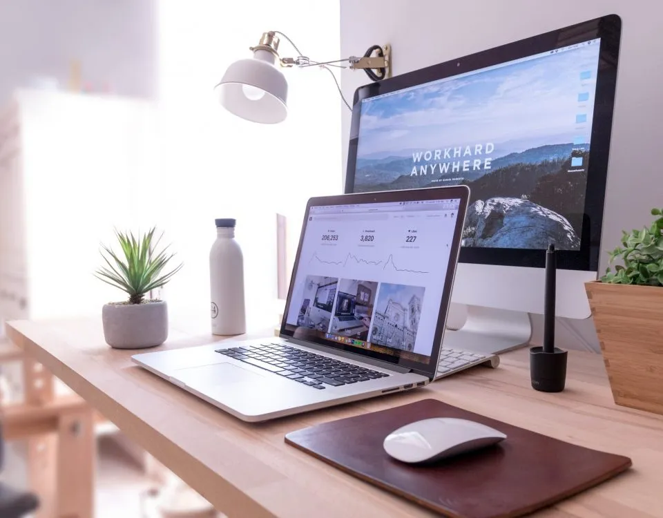MacBook Pro on table beside white iMac and Magic Mouse